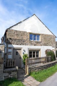 a stone house with a wooden fence in front of it at Thornes Cottage in Huddersfield