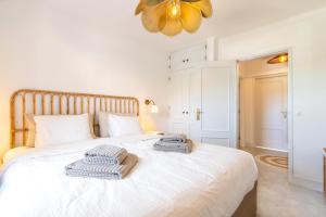 a bedroom with a white bed with towels on it at Casa Golden Bamboo, private patio & 100m from the river! in Vila Nova de Milfontes
