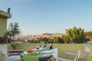 a table with a plate of fruit and wine on a balcony at Meros - Athenian Residencies in Athens