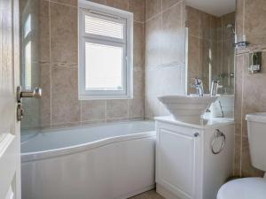 a bathroom with a tub and a sink and a toilet at Oak Lodge in Longhope +11 photos
