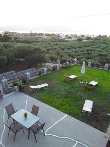 patio ze stołem i krzesłami oraz trawnikiem w obiekcie Marianos Apartments w mieście Kisamos