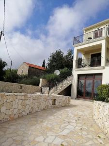 a white house with a stone wall and stairs at Villa Clio in Mánganos