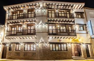Perales de Tajuña的住宿－Hotel Rural El Lagar de Nemesio，一座高大的砖砌建筑,晚上设有窗户和阳台