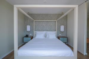 a bedroom with a white bed with two night stands at Hotel Vouga in Termas de Sao Pedro do Sul