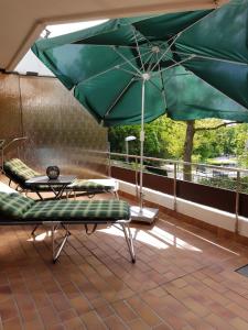 a green umbrella and a table on a balcony at Appartementresidenz am Kurpark Bad Salzuflen in Bad Salzuflen