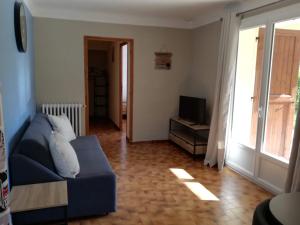 a living room with a blue couch and a television at Gites en Cevennes "Chez Steloune" in Génolhac