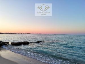 uma vista para o oceano a partir da praia ao pôr-do-sol em Jewel Matrouh Hotel em Marsa Matruh