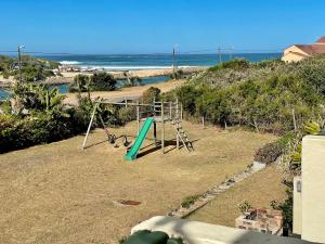 a playground on the beach with the ocean in the background at 39 Settler Sands Beachfront Accommodation Sea and River View in Port Alfred
