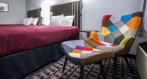 Habitación de hotel con cama y silla con edredón en Brick Lodge Atlanta/Norcross en Norcross