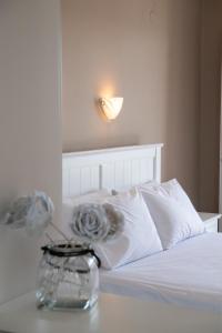 a bed with white sheets and a vase on a table at Spiros Sea View in Nydri