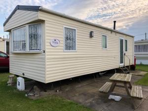 a tiny house is parked in a yard at Norfolk Lavender Caravan - Sleeps 4 - WiFi and Sky TV Included in Bacton