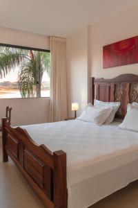 a bedroom with a large bed with a large window at BellaMinas Pousada in Guapé