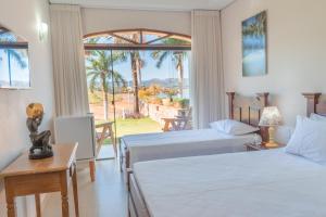 um quarto de hotel com duas camas e uma grande janela em BellaMinas Pousada em Guapé
