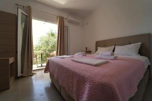 a bedroom with a bed with a pink blanket and a window at Meltemi in Parga