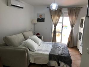 ein Schlafzimmer mit einem Bett, einem Sofa und einem Fenster in der Unterkunft ATICO SAN MARCOS in El Puerto de Santa María