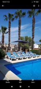 a group of chairs and palm trees next to a swimming pool at Estrella Del Mar Tranquil and spacious villa, convenient location 3-5 mins' walk to all amenities in Villacosta