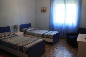 a room with two beds and a chair and a window at Casa Vacanze Ramo in Mazara del Vallo