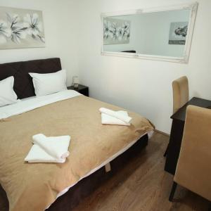 sypialnia z łóżkiem z dwoma białymi ręcznikami w obiekcie Apartments & Dream Rooms w Niszu