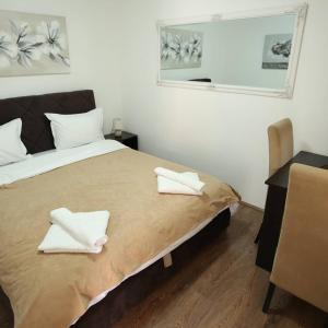 a bedroom with a bed with two white towels on it at Apartments & Dream Rooms in Niš