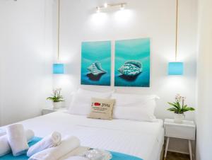 a bedroom with a white bed with three paintings on the wall at Georgia Villas in Skiathos