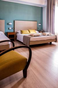 a bedroom with two beds and a chair at Albergo Cerchi in Tortona