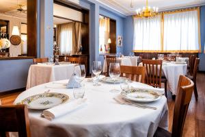 a restaurant with white tables and chairs and a chandelier at Albergo Cerchi in Tortona