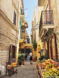 a man walking down a street with a fruit stand at Sunny Beach Bari in Bari