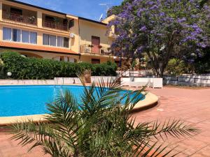 a swimming pool in front of a building with purple flowers at Great Sicily in Mondello