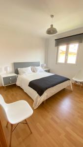 ein Schlafzimmer mit einem großen Bett und einem weißen Stuhl in der Unterkunft Duplex Playa Langosteira in Kap Finisterre
