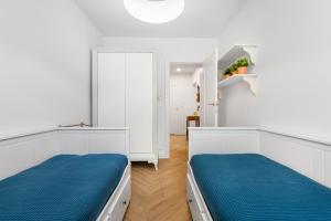 Holiday Sopot Apartment في سوبوت: سريرين في غرفة بيضاء مع ملاءات زرقاء