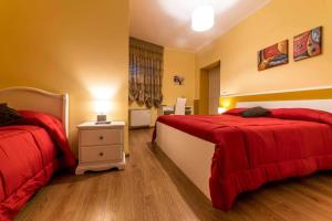 1 Schlafzimmer mit 2 Betten mit roten Bettdecken und einem Nachttisch in der Unterkunft BB Villa Giacomina in Tempone