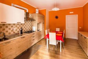 eine Küche mit orangefarbenen Wänden und einem roten Tisch mit Stühlen in der Unterkunft BB Villa Giacomina in Tempone