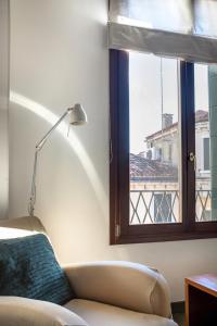 uma sala de estar com um sofá e uma janela em MANSARDINA - 1 min from Accademia - duplex stylish and cosy em Veneza
