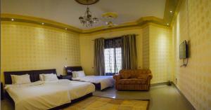 a bedroom with two beds and a chair and a window at Arabian Lodges in Bahawalpur