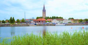 un río con barcos en una ciudad con iglesia en Vänerport Lakefront Hotell en Mariestad
