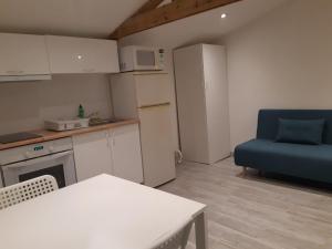 cocina con mesa y silla azul en Logement proche Lyon-aéroport-Centrale Bugey, en Dagneux