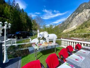 a table with red chairs and an elephant statue on a balcony at Boxenstopp Gurtnellen in Gurtnellen