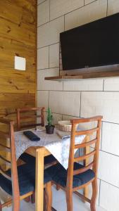 a dining room table with chairs and a flat screen tv at Pousada Vó Ciloca in Praia Grande