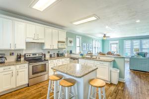 a kitchen with white cabinets and a island with bar stools at Lighthouse By The Sea in St. George Island