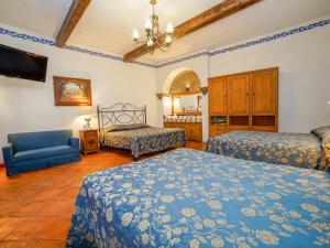 a bedroom with two beds and a blue couch at Hotel Mansión Virreyes by Rotamundos in San Miguel de Allende