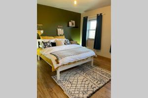 a bedroom with green walls and a bed with a rug at Mary-Jane’s Cottage in Omagh
