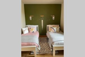 two beds in a room with green walls at Mary-Jane’s Cottage in Omagh