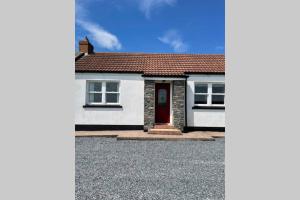 a white house with a red door and a driveway at Mary-Jane’s Cottage in Omagh