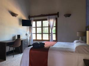 a bedroom with a bed and a desk and a window at Hotel Posada San Miguel in Antigua Guatemala
