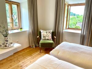 a bedroom with a bed and a chair and a window at Mama Trixi‘s Ferienwohnungen in Amlach