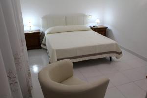 1 dormitorio con 1 cama y 1 silla en Villa Bice, en Pulsano