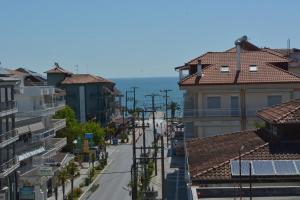 eine Stadtstraße mit Gebäuden und dem Meer im Hintergrund in der Unterkunft Villa Georgio Paralia in Paralia Katerinis
