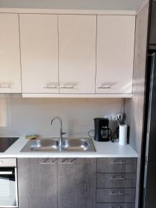 una cocina con armarios blancos y fregadero en Nicole Apartment, en Perdika