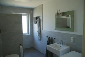 a bathroom with a sink and a toilet and a mirror at Ferienwohnungen Weide-Meer-Watt in Großheide +40 photos