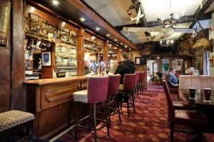 a bar with chairs and a man standing at a counter at Mahon's Hotel in Irvinestown